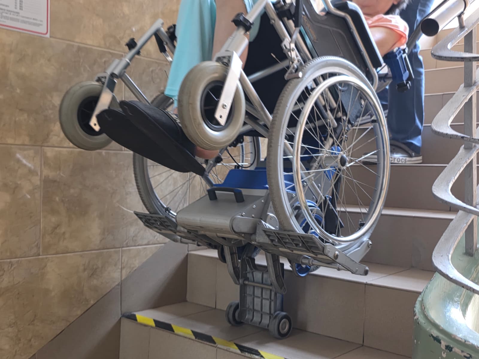 Transport osoby na wózku po schodach przy użyciu specjalistycznego urządzenia